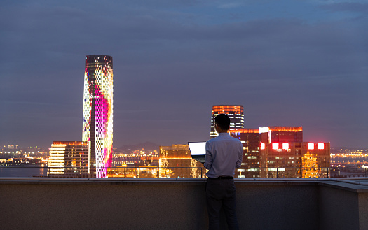 Businessman standing on the rooftop and using laptop.