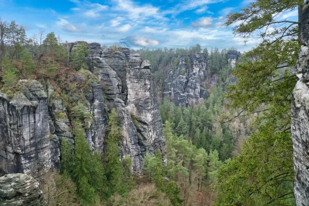 Rugged rocks on the Basteibridge. Wide view over trees and mountains. National park in Germany