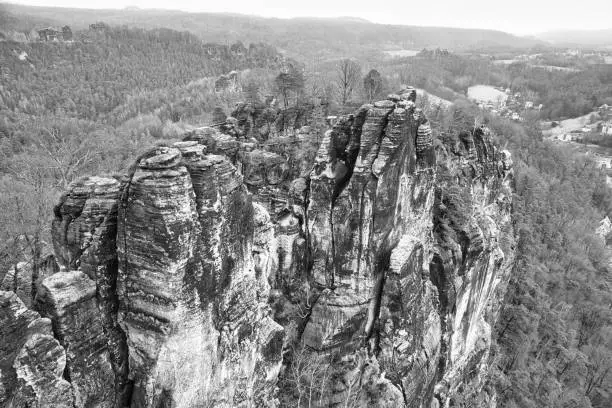 Jagged rocks at the Basteibridge. Wide view over trees and mountains. National park in Germany
