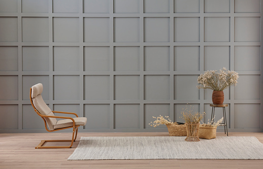 Vase of cotton flower and wicker chair decoration in front of the modern grey wall, carpet style.