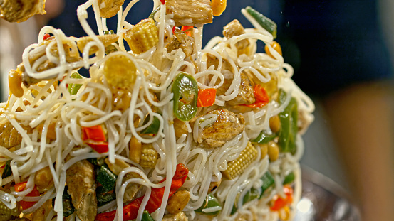 Close-up of a chicken noodle stir fry being tossed in a wok.