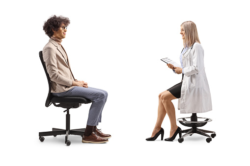 Profile shot of a man sitting and having a conversation with a female doctor isolated on white background