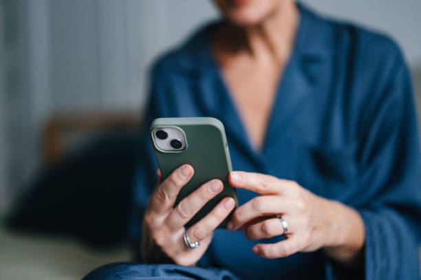 istock Anonymous Older Woman Holding and Using Mobile Phone in Bed 2080405206