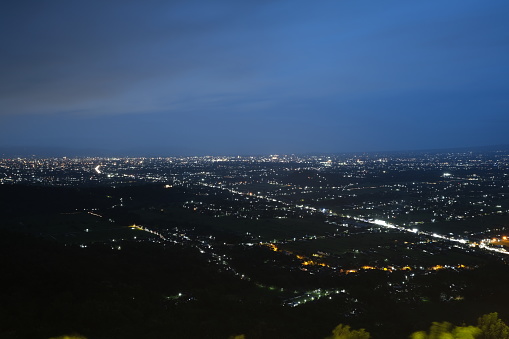 Night view of a sprawling cityscape illuminated by lights, seen from a mountain overlook