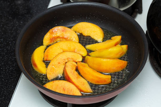 Frying peach slices in butter in a frying pan