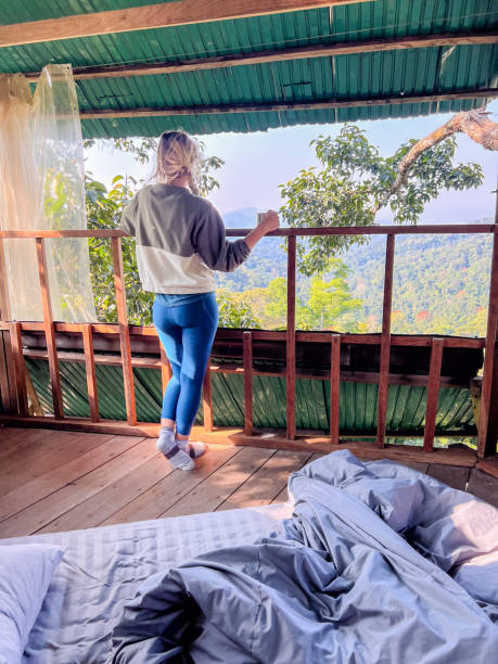 istock One woman enjoying nature from a bed in a tree house 2080457031