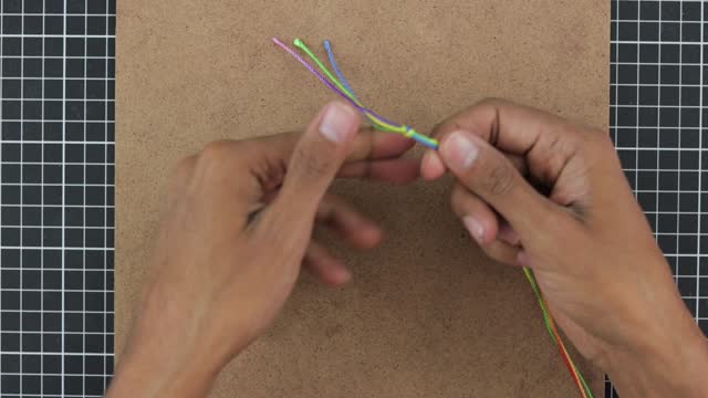 close-up creating macrame bracelet, skilled hands weave colorful rainbow thread