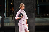 Stylish fashion woman wearing pink suit, shirt and shorts, standing confidently against a city backdrop. Urban street style allure