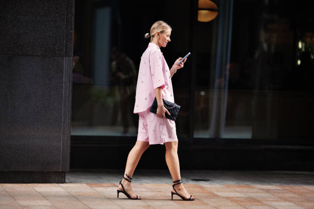 istock Young trendy woman texting on her phone, captivated by the mobile screen while walking on a city street. Urban connectivity and modern lifestyle 2080461815