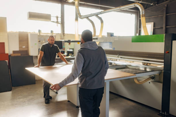 istock Two experienced workers work as a team on woodworking and use Industrial cutting machine for automatic wood cutting. Wooden furniture production 2080466669