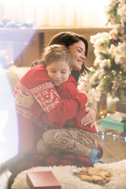 istock Mother and son hug while sitting in front of the Christmas tree 2080527867
