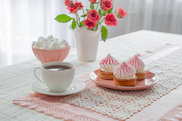 cup of coffee with dessert and roses on table