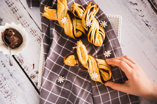 Kids hand taking delicious Palmiers with chocolate on wooden background. Easter concept, bunny