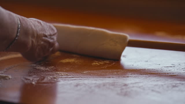 Close-up of Female Hands Flattening Dough Using Rolling Pin as Part of Preparation of a Traditional Balkan Dish Known as Borek