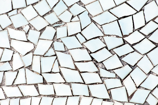 Broken white tiles pattern, wall or flooring decoration . Traditional trencadis geometric decoration, construction material, full frame abstract view. Spain.