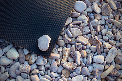 Нoga mat on a sandy pebble beach. Healthy lifestyle, harmony concept