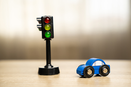A toy blue car near a traffic light on the table. Traffic and driving rules concept