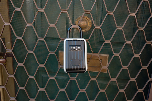 Close-up of a lock on a metal door, with main wooden door behind. The lock is not used in a correct location.