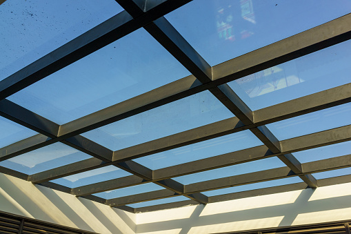 A modern roof structure built with steel and glass is frequently utilized in contemporary house construction to maximize natural sunlight. Low angle view.