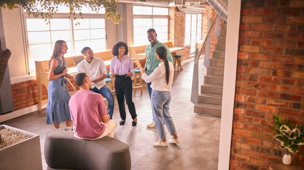 Multi-Cultural Business Team Having Informal Meeting Standing In Modern Open Plan Office Together