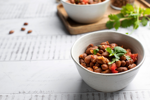 Vegetarian dish of stewed pink beans and tomatoes. A delicious bean dish served on a wooden table.