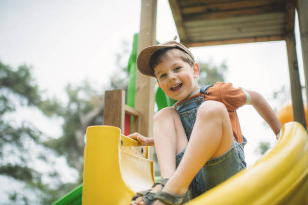 istock Little boy sliding at a playground in summer park 2080662603