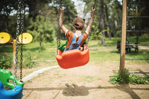 Happy child girl on swing, summer time. Life Events.  Retro toned, Soft focus effect