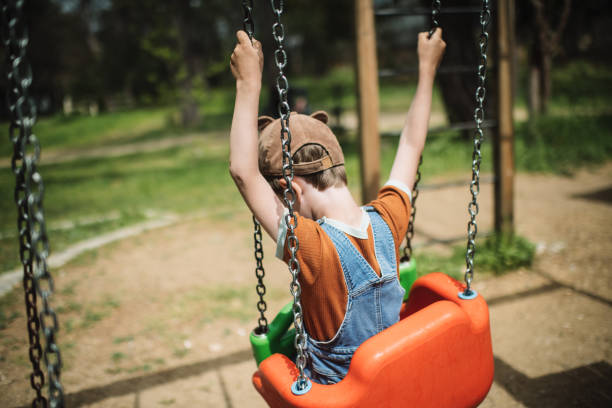istock Little boy swinging at a playground in summer park 2080665215