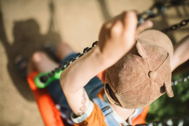 Little boy swinging at a playground in summer park