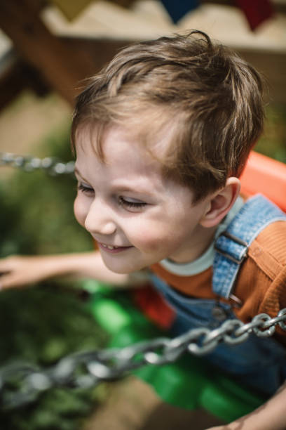 istock Little boy swinging at a playground in summer park 2080665755