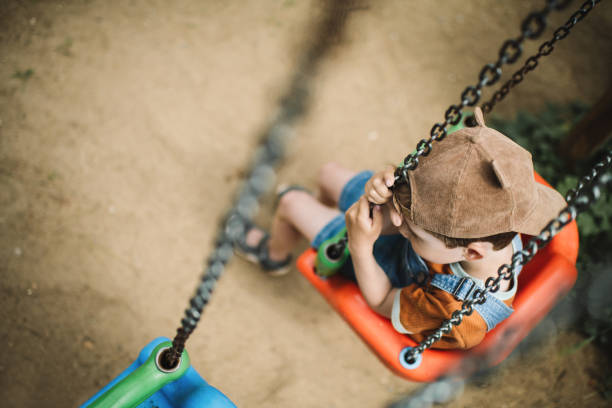 istock Little boy swinging at a playground in summer park 2080667319