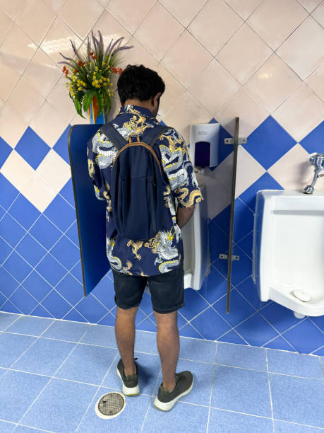 imagen de un hombre de pie en una fila de urinarios en inodoros de baños públicos, urinarios de cerámica blanca en diferentes niveles para niños y adultos, particiones de privacidad, salpicadero de fondo, urinarios higiénicos limpios con desagües y d - rough waters fotografías e imágenes de stock