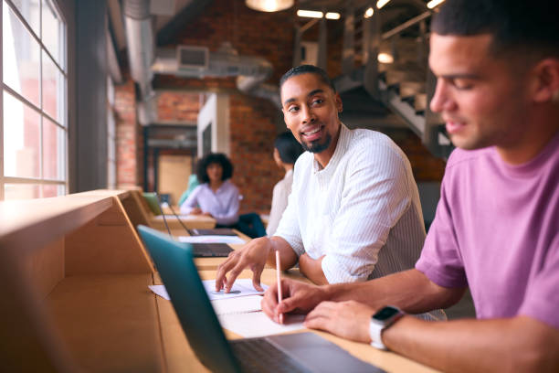 istock Two Businessmen With Laptop Meeting In Office Discussing Documents With Colleagues In Background 2080692992