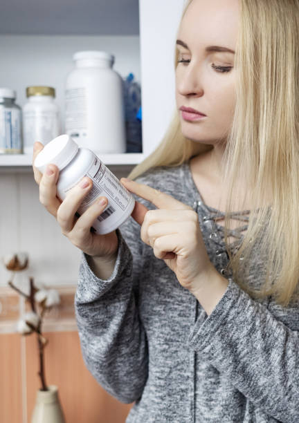 istock Girl studies dietary supplements. Reading the instructions on a bottle of vitamin complex. Nutritional supplement for hair loss and  weakened immunity. Self-prescription of drugs and harm to health 2080699357