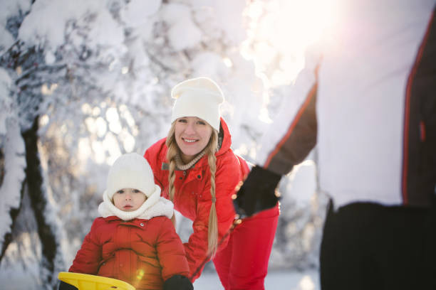 istock Winter walk: parents sledding with their son. A father pulls a sled with a young son on a snowy day, and a mother pushes. 2080730477