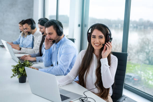 istock Call center agent woman with headset working on support hotline in office with group of customer support operators. 2080732124