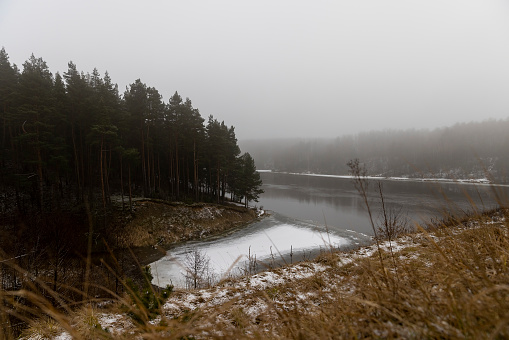river in winter, river bank and water in winter in foggy weather