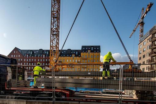 Stockholm, Sweden March 4, 2024 Workers handle a large cast cement block from a truck onto a crane in the Sodermalm district.