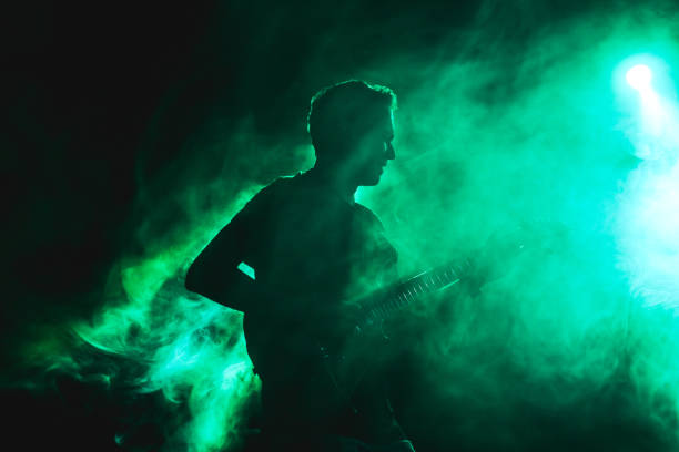 silhouette d’un guitariste sur scène avec des effets de lumière et de fumée. - artiste-de-spectacle photos et images de collection