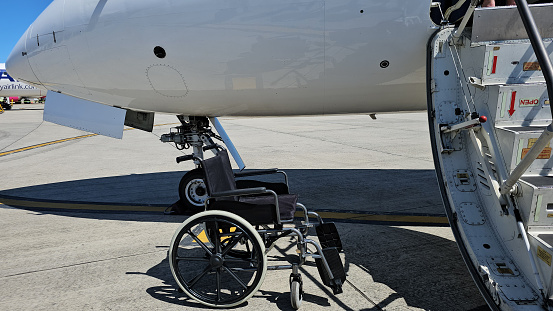 Wheelchair next to an airplane at the airport landing zone. Flight and rules for people with disabilities