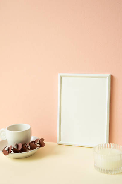istock White blank picture frame with coffee cup, candle on ivory table. pink wall background 2080764103