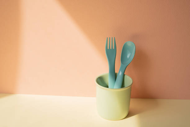 istock Kitchen blue cutlery fork and spoon in holder on ivory table. pink wall background 2080765346