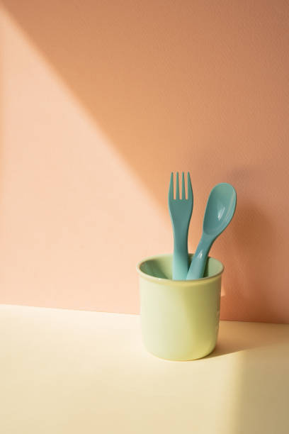istock Kitchen blue cutlery fork and spoon in holder on ivory table. pink wall background 2080766189