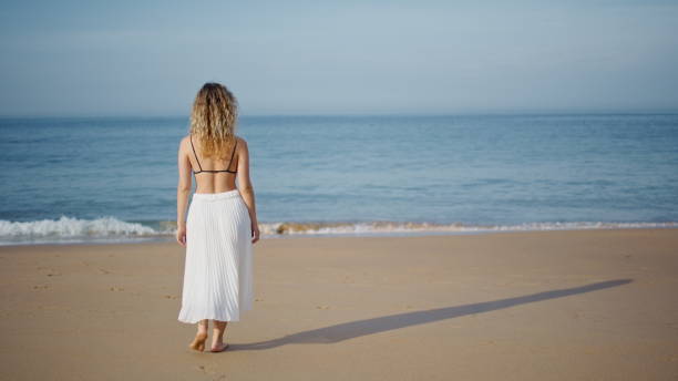 istock Relaxed girl stepping sand beach relaxing at evening sunlight back view. 2080771926