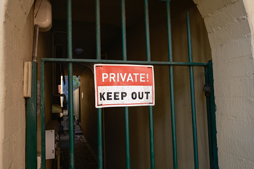 Metal privacy sign on a green gate.