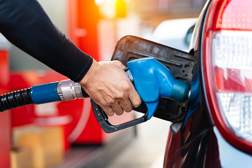 A man pours gasoline into the gas tank of a car at a gas station. Fuel for cars, transport.