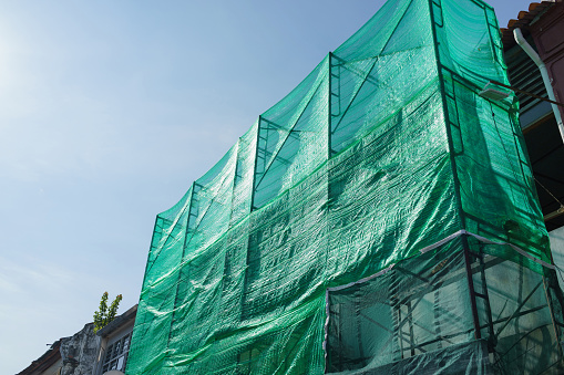 Scaffolding and green open-meshed material cover the construction of heritage houses in Georgetown, Penang, undergoing renovation.