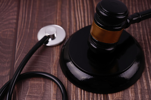 A gavel and stethoscope placed on a wooden table.