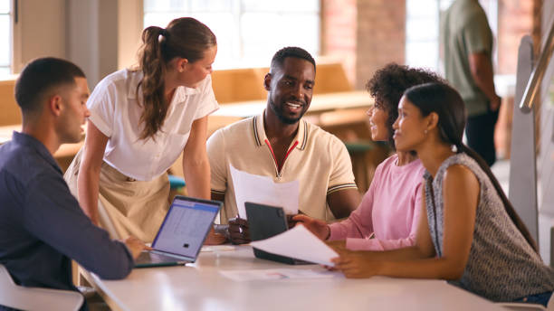 istock Multi-Cultural Business Team Meeting Around Desk In Modern Open Plan Office Discussing Documents 2080799362