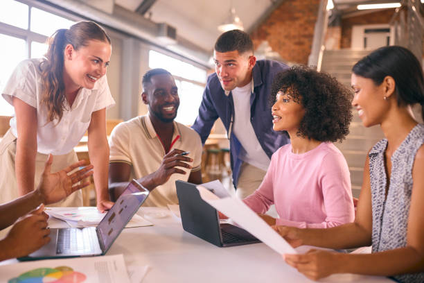 istock Multi-Cultural Business Team Meeting Around Desk In Modern Open Plan Office Discussing Documents 2080806028